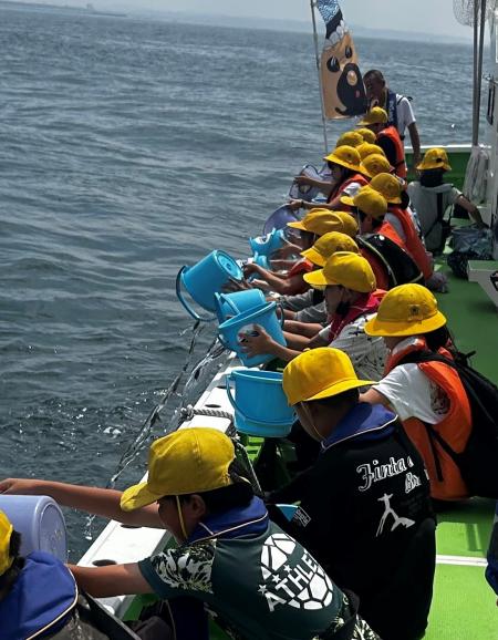 稚魚を放流する平塚市立港小学校の児童